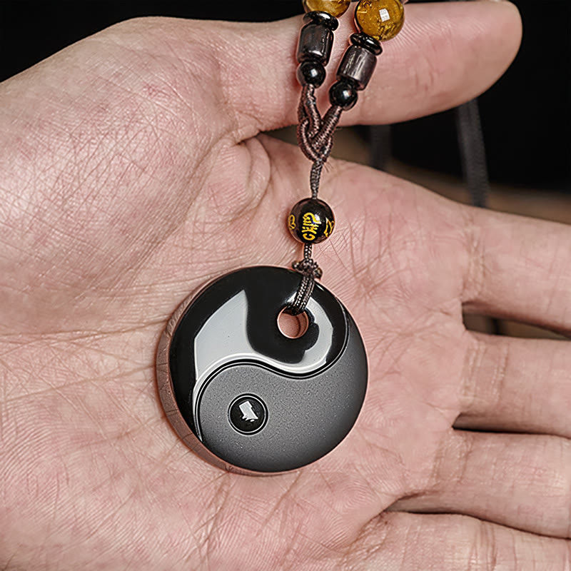 Yin Yang Obsidian Pendant held in hand, beaded cord with amber accents, zen necklace