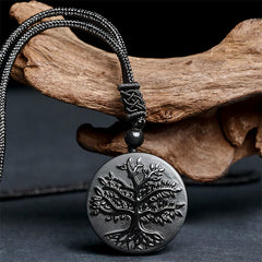 Tree of Life Black Obsidian Necklace – pendant resting on driftwood showing carved tree pattern, obsidian jewelry