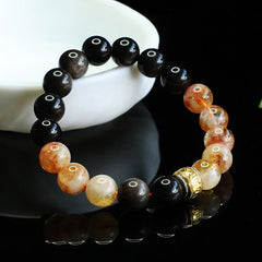 Obsidian Citrine Mantra Bracelet - Black and amber beads with gold mantra charm on dark reflective surface, crystal healing