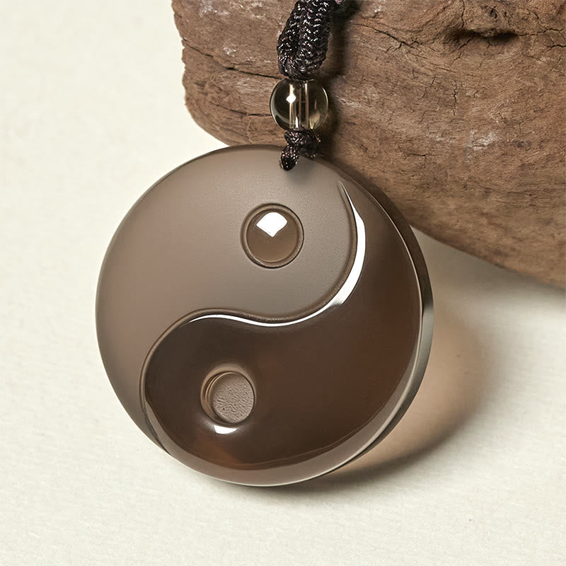 Black Obsidian Nine-Character Mantra Necklace – Polished obsidian Yin-Yang necklace with driftwood prop, studio jewelry photo