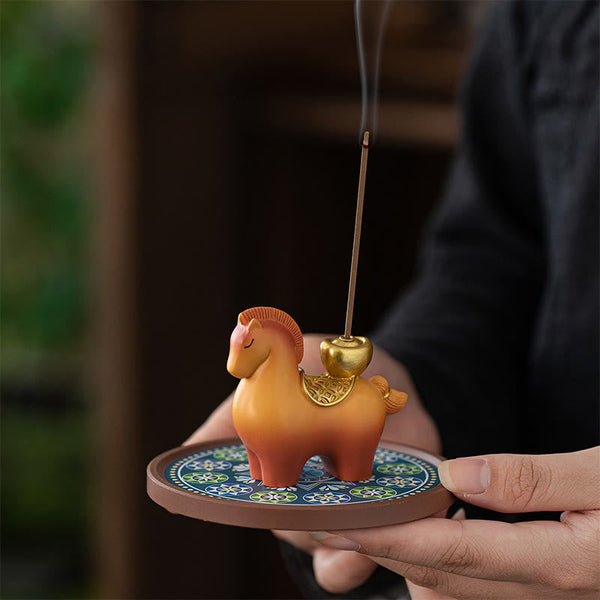 Year of Horse Ingot Incense Burner – Amber horse with gold saddle on blue base, held in cupped hands with smoke, incense burner