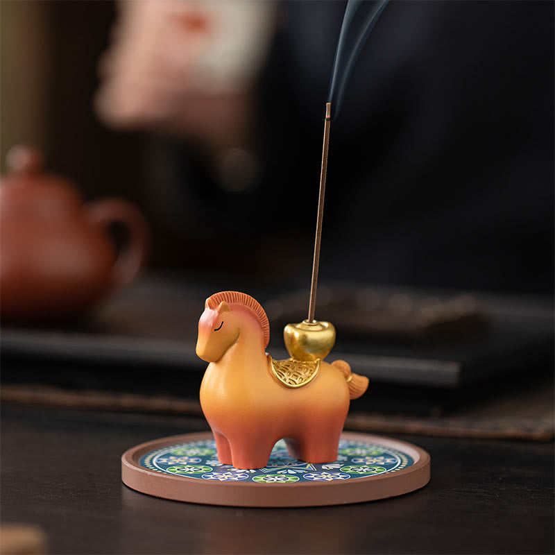 Year of Horse Ingot Incense Burner – Orange horse incense holder with gold saddle on patterned base, teapot nearby, incense burner