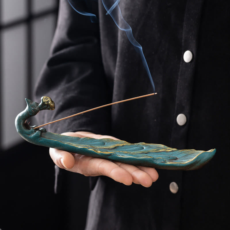 Peacock Shape Ceramic Incense Burner – Teal peacock incense holder cradled in hand with burning stick and smoke, ceramic incense holder