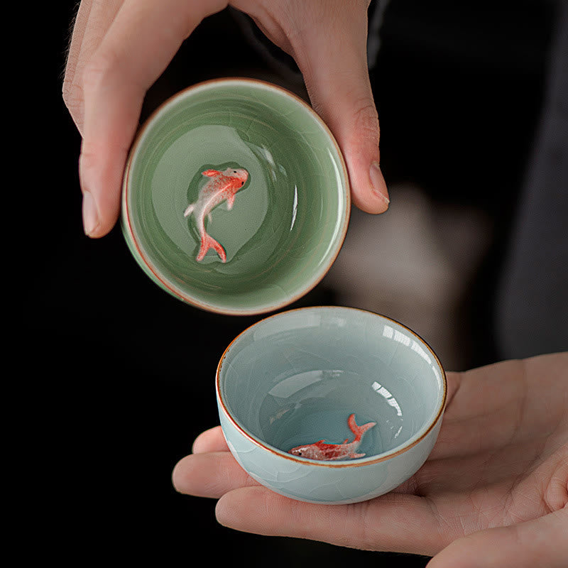 Hand Painted Koi Fish Ceramic Teacup – two celadon cups in hands with koi visible, hand painted tea set