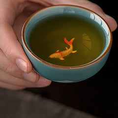 Hand Painted Koi Fish Ceramic Teacup – hand holding cup with koi fish illusion in tea, ceramic gongfu cup