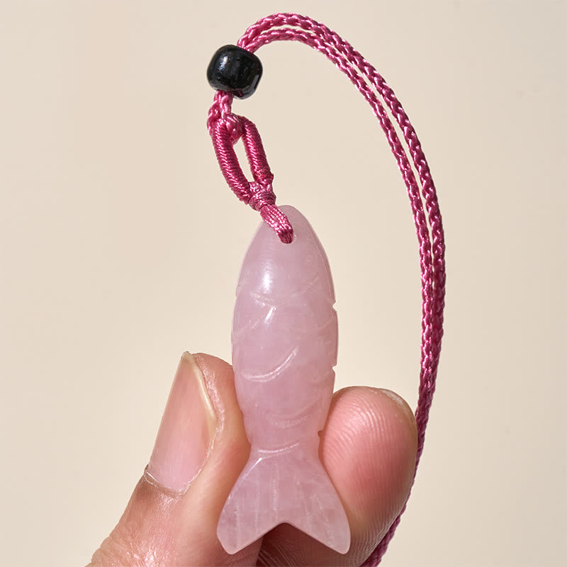 Koi Fish Crystal Necklace Pendant – translucent pink koi held in fingers on neutral bg, rose quartz jewelry