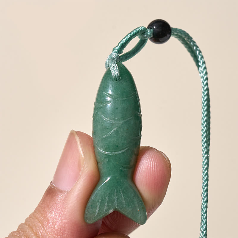 Koi Fish Crystal Necklace Pendant – green agate pendant held in fingers frontal neutral bg, aventurine fish