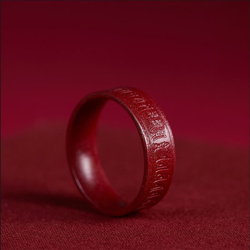 Cinnabar Heart Sutra Om Mani Padme Hum Blessing Ring – upright on red fabric showing carved mantra around band, cinnabar jewelry