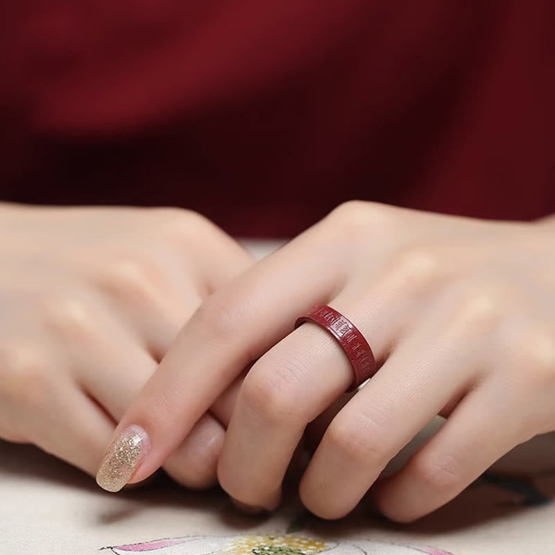 Cinnabar Heart Sutra Om Mani Padme Hum Blessing Ring – worn on hand with gold nail accent near floral fabric, cinnabar ring