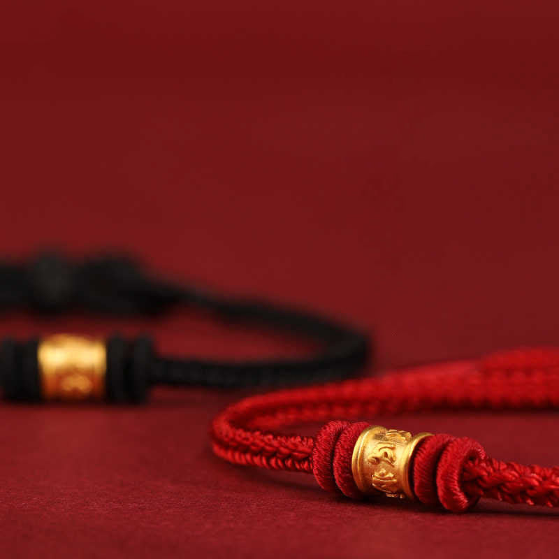 999 Gold Om Mani Padme Hum Red String Bracelet – red bracelet with gold bead in focus against black bracelet on red backdrop, lucky bracelet