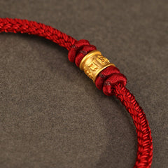 999 Gold Om Mani Padme Hum Red String Bracelet – macro close-up of embossed gold bead and red cord texture, gold bead bracelet