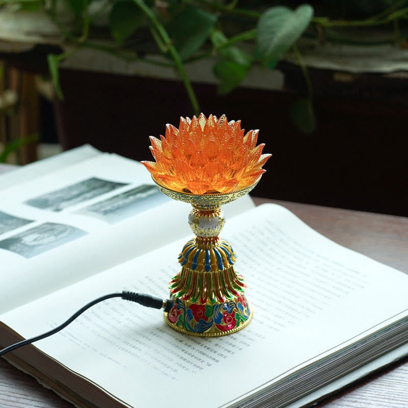 Lotus Liuli Glass Decor - illuminated orange glass lotus flower lamp with gold enamel base on open book, warm amber LED glow