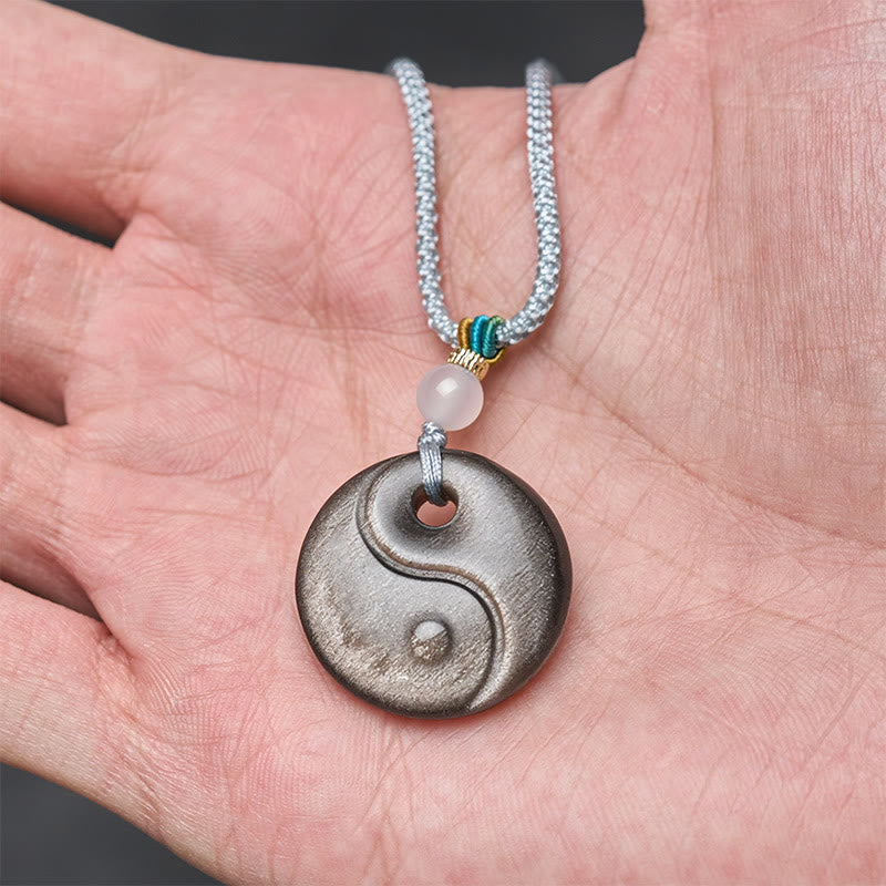 Silver Sheen Obsidian Yin Yang Pendant – held in palm, scale reference amulet