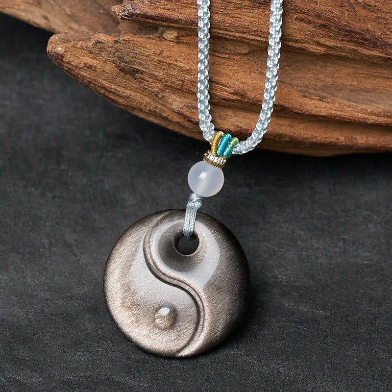 Silver Sheen Obsidian Yin Yang Pendant – 3/4 angle on wood, carved taijitu amulet