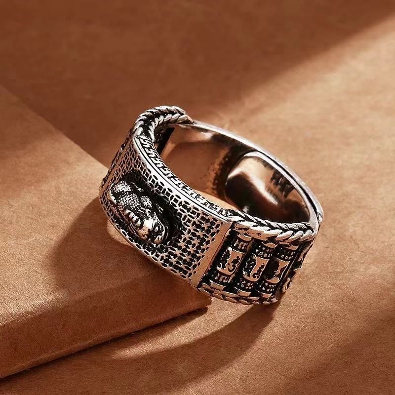 Feng Shui PiXiu Wealth Prayer Wheels Couple Ring – angled close-up on brown paper showing intricate engraving and braided edge detail