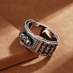 Feng Shui PiXiu Wealth Prayer Wheels Couple Ring – angled close-up on brown paper showing intricate engraving and braided edge detail