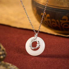 Koi Fish Peace Buckle Necklace – jade disc with silver koi overlay, crystals, on burgundy velvet with props