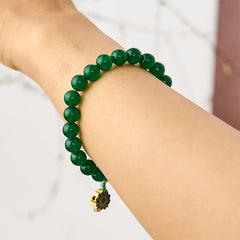 Green Agate Lotus Charm Beaded Bracelet - Worn on wrist with dangling lotus pendant against marble, healing stone bracelet