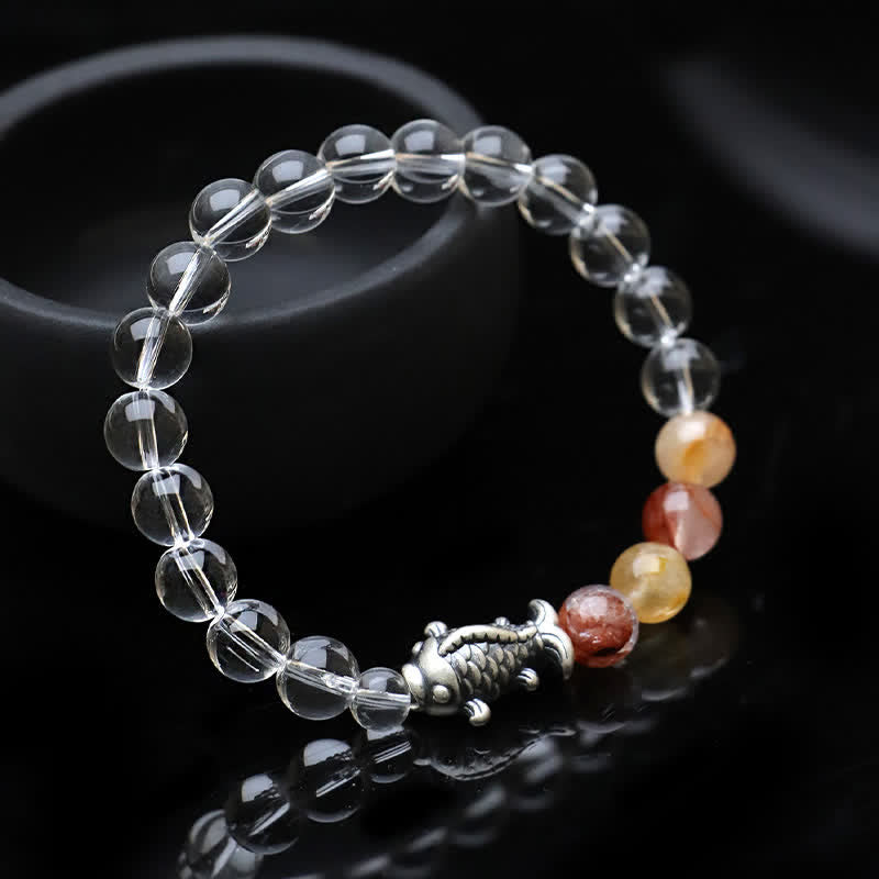 Clear Quartz Koi Fish Bracelet – low-angle macro on black mirror, crystal beads with amber accents, silver koi charm