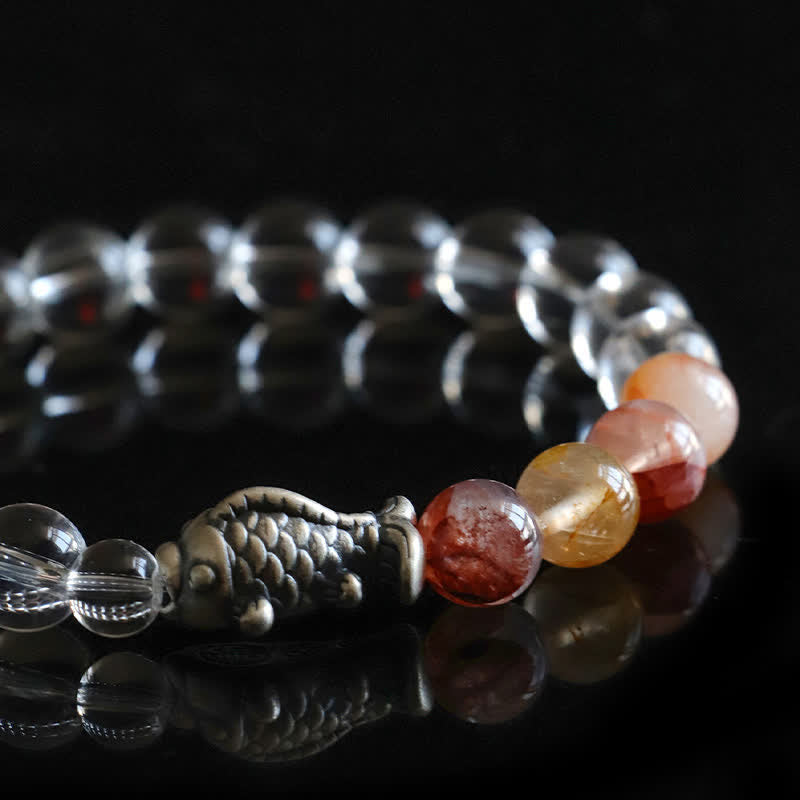 Clear Quartz Koi Fish Bracelet – shallow angle side-profile on black mirror, crystal beads, silver koi, bokeh