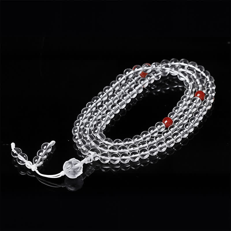 Liuli Lotus 108 Bead Mala - spiral coil on black reflective surface, transparent beads with red accents