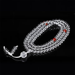 Liuli Lotus 108 Bead Mala - spiral coil on black reflective surface, transparent beads with red accents