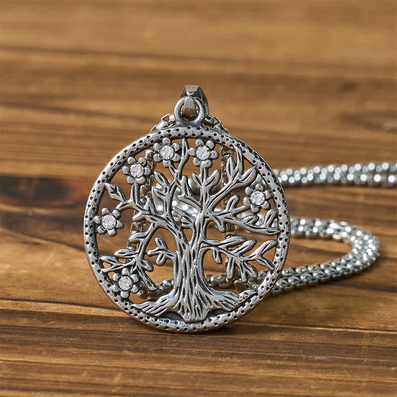 Tree of Life Titanium Steel Necklace – Silver pendant flat lay on wood with chain coiled behind, detail