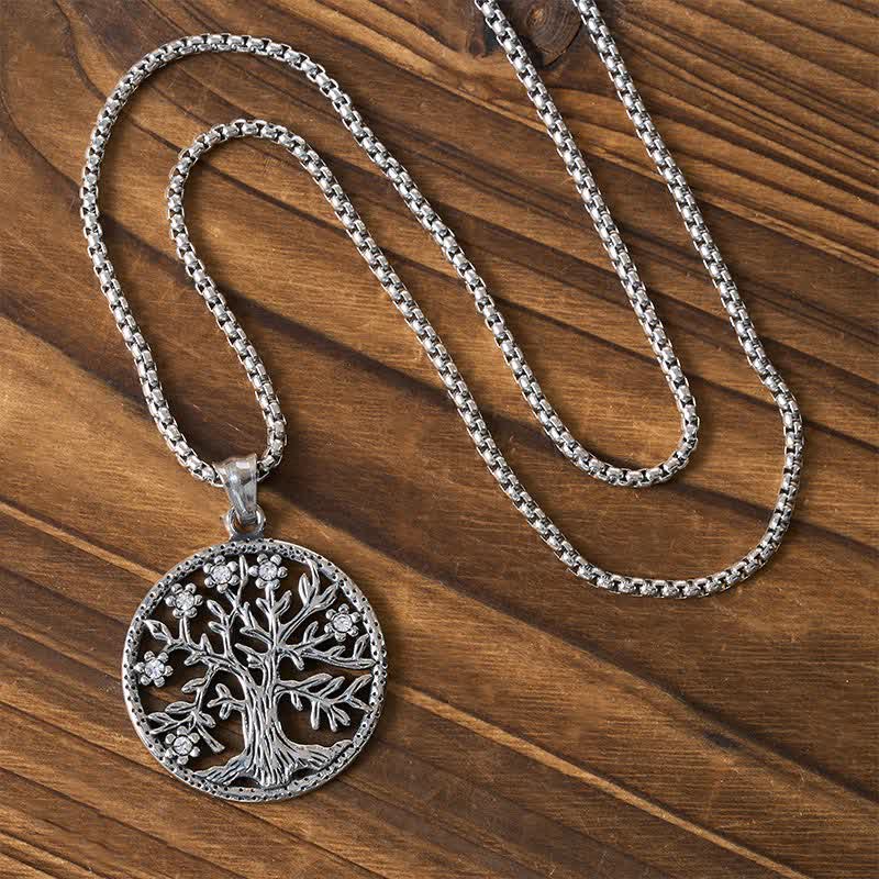 Tree of Life Titanium Steel Necklace – Silver necklace with chain arranged on dark wood, overhead view