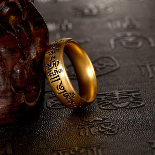 Om Mani Padme Hum Ring – Tibetan engraved gold band with dark textured backdrop, spiritual jewelry