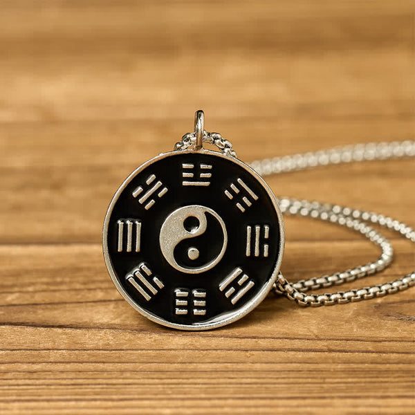 Yin Yang Bagua Pendant - Angled view of oxidized silver yin yang medallion on wood grain, bagua necklace