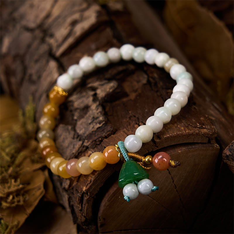Multicolor jade bracelet with carved green lotus charm on dark wood, white yellow amber gradient beads