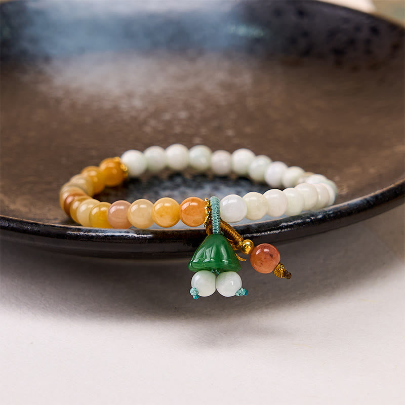 Ombre stone bead bracelet with carved jade green charm on wrist, white to amber gradient beads
