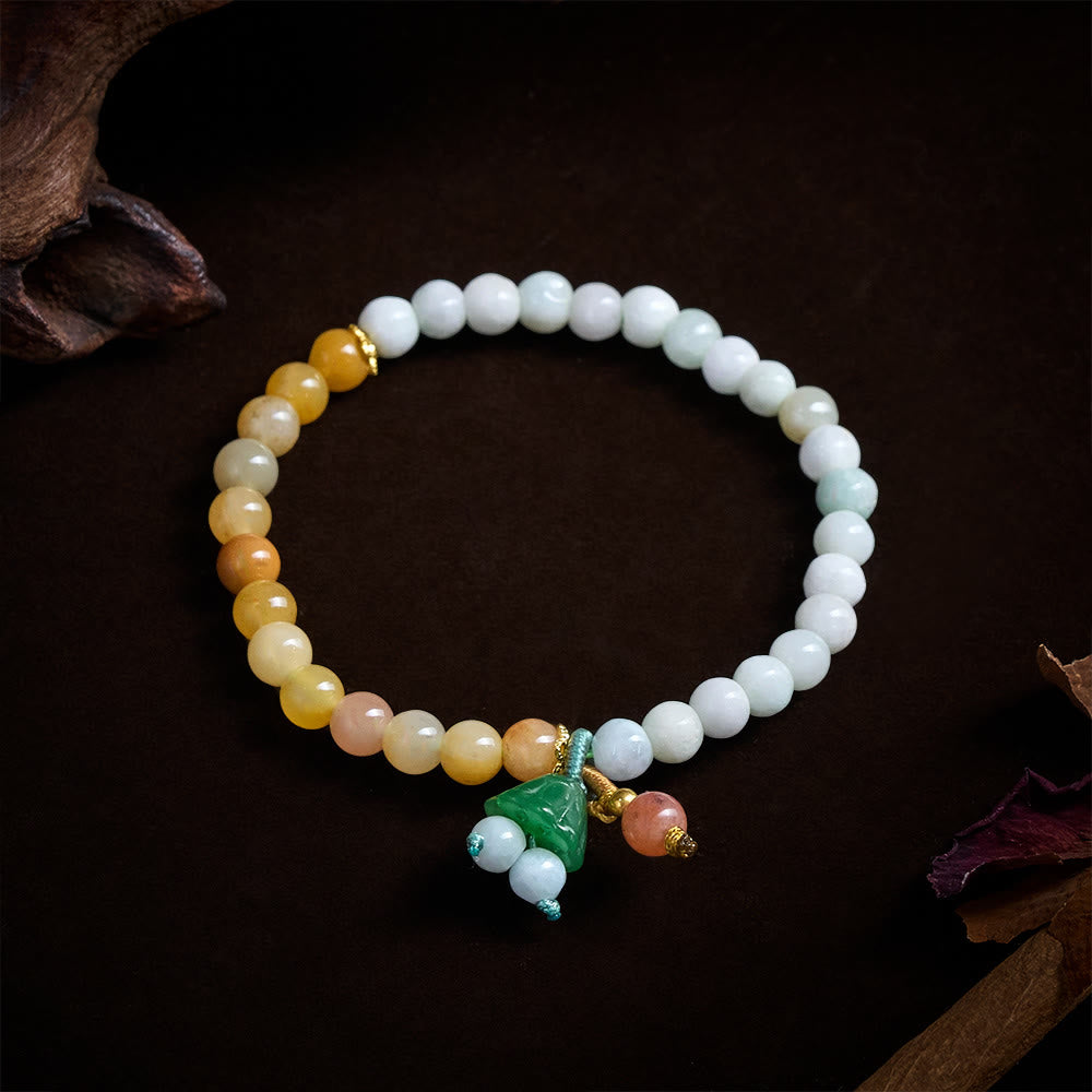 Gradient jade bead bracelet with green carved lotus pod charm on dark ceramic dish, jade bracelet