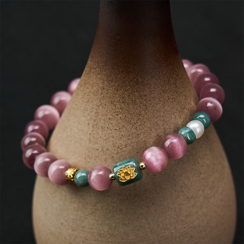 Purple Cat’s Eye Lotus Enlightenment Bracelet – Close-up of purple cat’s eye beads with gold lotus symbol and jade accents on dark wood, healing bracelet