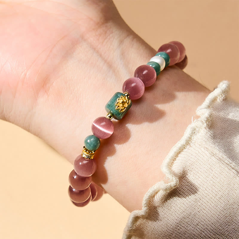 Purple Cat’s Eye Lotus Enlightenment Bracelet – Wrist-worn close-up of pink cat’s eye bracelet with gold lotus centerpiece and gold spacers