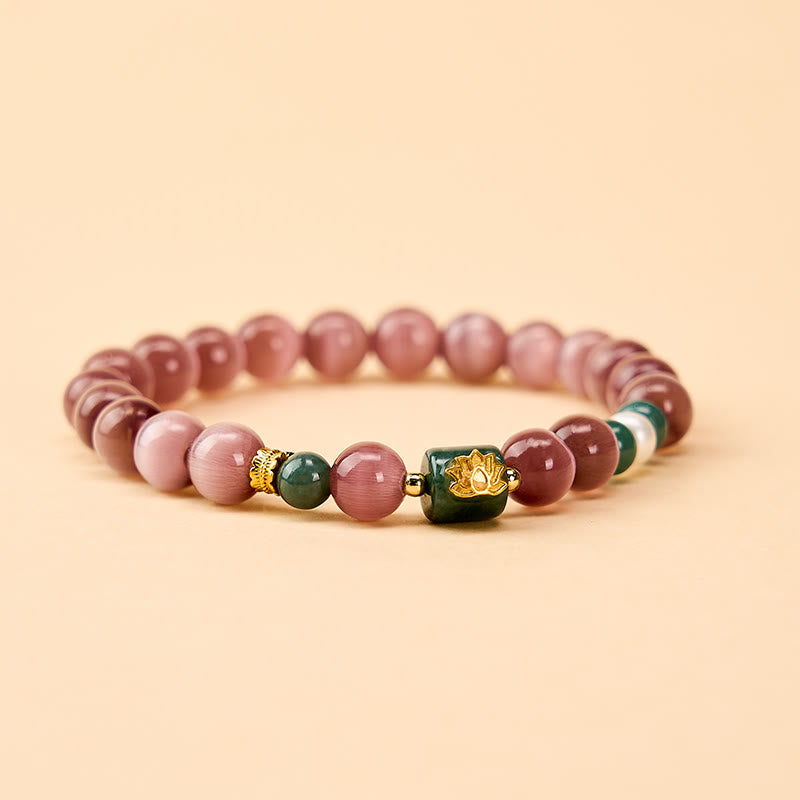 Purple Cat’s Eye Lotus Enlightenment Bracelet – Flat lay view showing mauve cat’s eye beads, gold lotus focal bead and green accents, gemstone bracelet