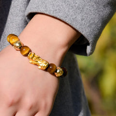 Natural Tiger Eye Pixiu Fu Om Mani Padme Hum Bracelet – wrist model in grey sweater outdoors showing golden Pixiu tiger eye