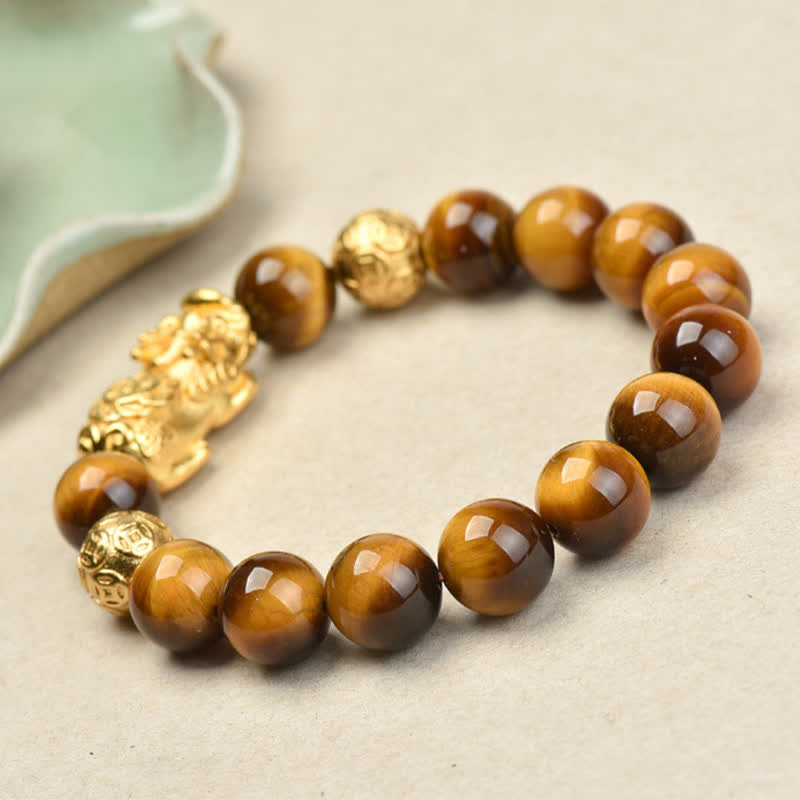 Natural Tiger Eye Pixiu Fu Om Mani Padme Hum Bracelet – golden Pixiu with celadon dish, angled side view on beige