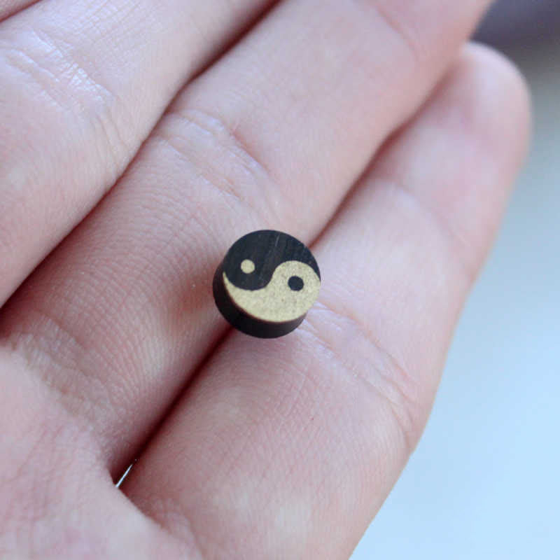 Ebony Wood Yin Yang Stud Earrings - Wood yin yang disc on fingers showing natural tan and black tones, handmade earrings
