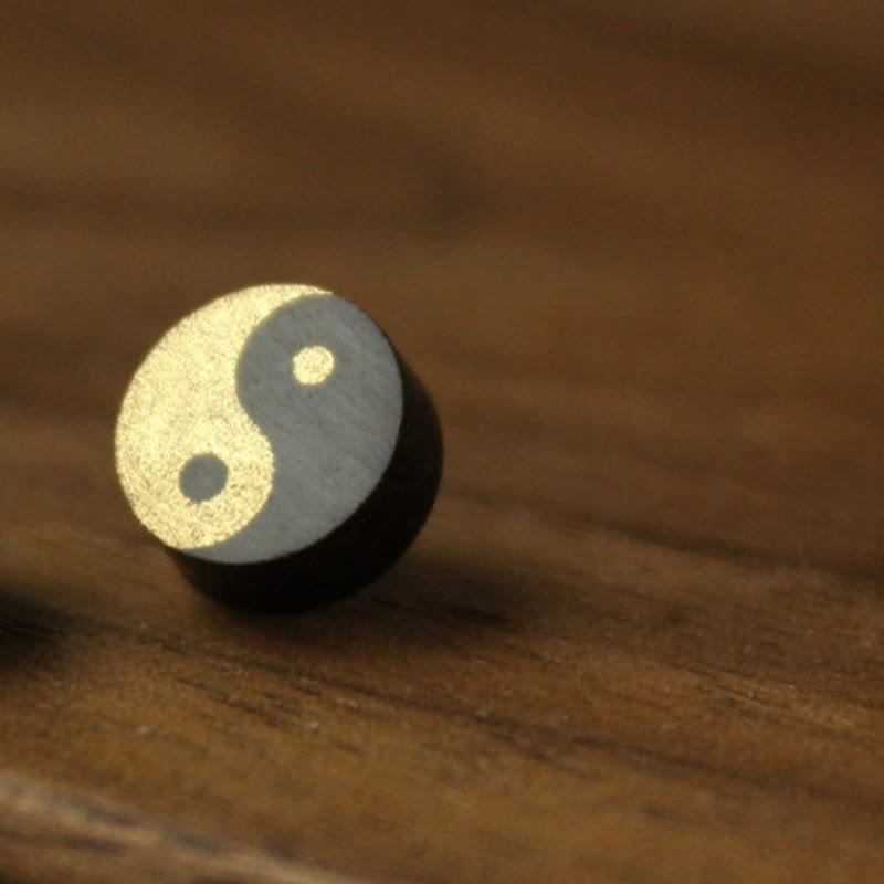 Ebony Wood Yin Yang Stud Earrings - Gold textured yin yang wood bead on warm wooden table, artisan meditation jewelry