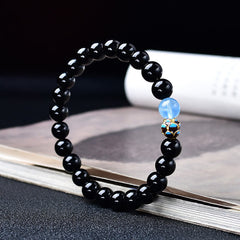 Black Obsidian Lotus Purification Bracelet - arced view on open book showing enamel spacer bead, mindfulness
