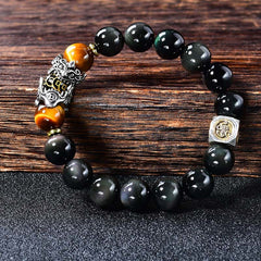 Natural Black Obsidian PiXiu Tiger's Eye Bracelet – bracelet on dark wood showing PiXiu detail, tiger eye and obsidian beads