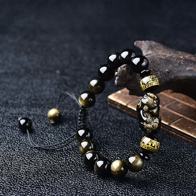 Gold Sheen Obsidian PiXiu Bracelet – Flat lay on black cloth, gold sheen obsidian beads, carved Pi Xiu, mantra gold spacers