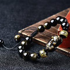 Gold Sheen Obsidian PiXiu Bracelet – Leaning on red box, gold flash obsidian beads, Pi Xiu wealth charm, black cord