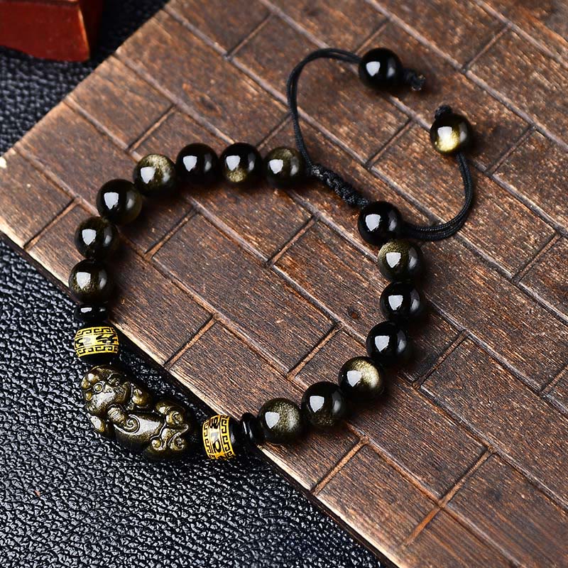 Gold Sheen Obsidian PiXiu Bracelet – Top view on bamboo mat, adjustable pull cord, glossy black gold beads, feng shui