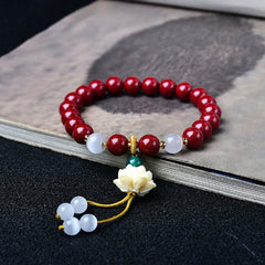 Cinnabar Cat's Eye Lotus Blessing Bracelet - red beads with carved lotus charm on ink-wash book, spiritual jewelry
