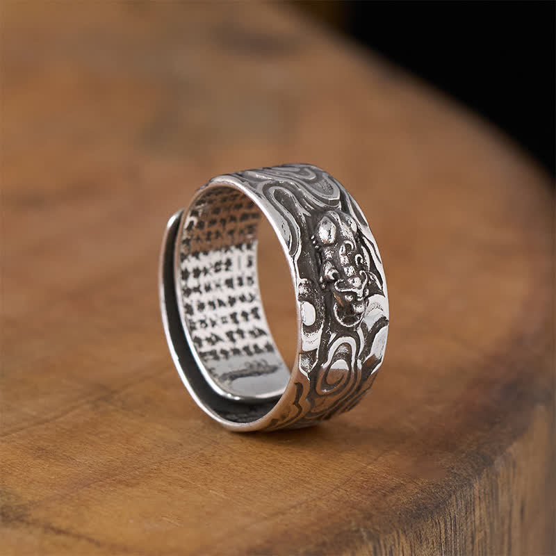 PiXiu Heart Sutra Copper Ring – All silver variant tilted on brown wood, wide band, Heart Sutra interior engraving