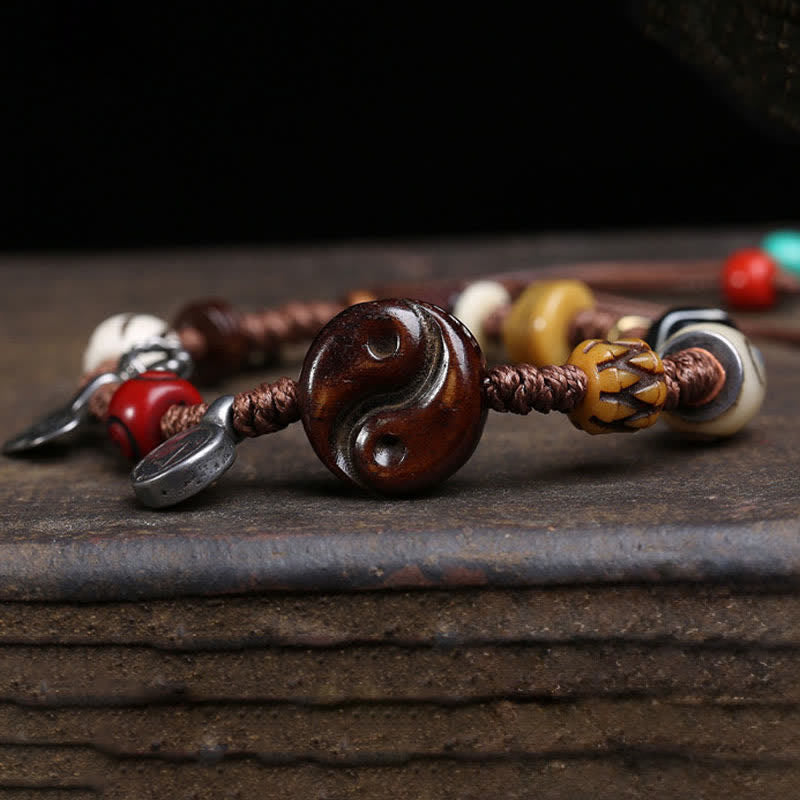 Yin Yang Bone Bracelet - macro of carved wooden yin yang bead on brown braided rope