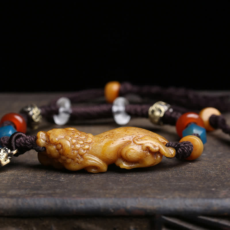Bone PiXiu Braided Rope Bracelet – Close-up of carved bone Pi Xiu, textured detail, dark background, wealth talisman