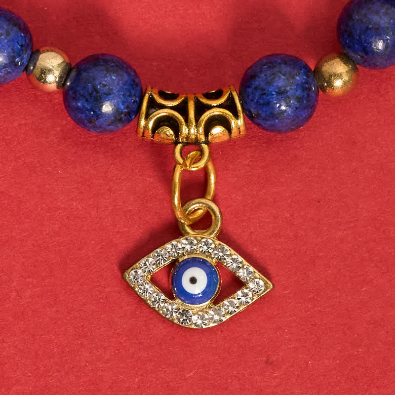 Lapis Lazuli Bracelet – Blue lapis lazuli bead bracelet with gold evil eye close-up, red fabric